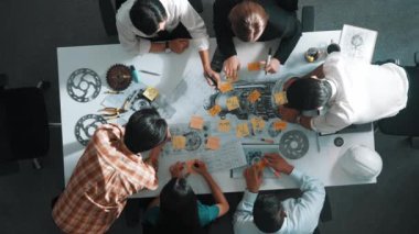 Üstten görünüşlü akıllı mühendis ekibi metal teçhizatlı, hesap makineli, yapışkan notlu türbin motor yapısı hakkında konuşuyor. Bir grup teknisyen toplantıda not alıyor. Hizalama.