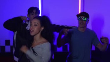 Gündelik gömlekli, gözlüklü, neon ışıkla dans eden farklı insanlar. Gece kulübünde dans ederken kameraya bakıp sokak dansı yapan çok kültürlü break dansçı. Mutluluk.