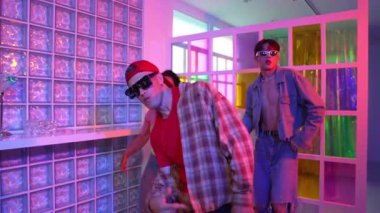 Değişik takımlarla dans ederken süslü gözlük takan yakışıklı hippi serbest stil müzikle mutlulukla dans ediyor. Beyaz hipster kulüpte parlak neon ışıkta sokak dansı yapıyor. Mutluluk.