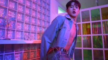 Çekici Asyalı sanatçı parlak neon ışıkta adım atıyor. Kameraya özgüvenle bakarken serbest stil müzikle dans eden yakışıklı break dans. Profesyonel hippi rahatla. Mutluluk.