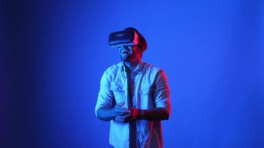 Oyun sahnesini temizlemek ya da maçı kazanmak için VR gözlükleri ve günlük kıyafetleriyle kutlama yapan çekici bir oyuncu. Akıllı iş adamı başarılı projeyi ya da satışları artırmayı kutluyor. Teknoloji. Aygıt.