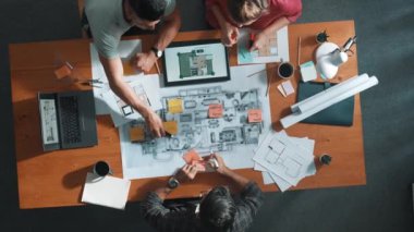 Bina planına bakarken inşaat mühendisinin elindeki belgelerin en alttaki görüntüsü. Mimarlık takımının fikir üretme ve planlama alanındaki hava görüşü masada planlı otururken. Sempozyum.