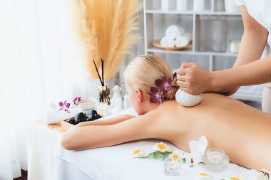 Sıcak bitkisel top spa masaj vücut tedavisi, masör kadın vücuduna nazikçe şifalı bitki torbası bastırıyor. Aromaterapi dinlenme sükuneti ve sükuneti kaplıca salonundaki atmosferi aydınlatıyor. Sessiz.