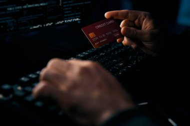 Mavi neon ışık odasındaki gizlilik sisteminde şifre kırma programı için kredi kartı veri tabanına yaklaşan kimliği belirsiz suçlunun el yapımı görüntüsü. Tahmin et..