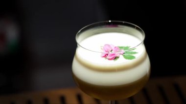 Tutkulu meyve suyu bardağında dönüşümlü, özel, ferahlatıcı, pembe çiçekle süslenmiş, lüks gece klübünde gece hayatı karışımı sergilenen bir içecek. Vinosity.