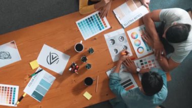 Proje yöneticisi renk paletleri seçerken tasarımcının tablete baktığı yukarıdan aşağıya hava görüntüsü. Profesyonel grafik tasarımının en üst görüntüsü ve logoya bakın. Yetenekli ekip grafikleri seçiyor. Sempozyum.