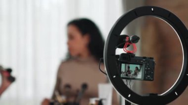 Arka plan kamera görüntüsü, iki kadın nüfuzlu kişinin canlı yayın yapan video görüntülerini kaydediyor. Makyaj, sosyal medya ya da blog. Çevrimiçi pazarlama yayını için kozmetik ürünleri olan genç bir kız.
