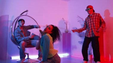 İspanyol hipster renkli kıyafetler giyer ve serbest stil müziğe el sallar. Profesyonel break dansçı neon ışıklarıyla ve modern stüdyo arkadaşlarıyla coşkuyla dans ediyor. Mutluluk.