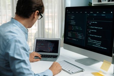 BT geliştiricisi, laptop üzerindeki yazılım geliştirme bilgisi üzerinde çalışırken pc ekran ile karşılaştırma yaparak sürüm uygulaması projesini güncellemek için yeni bir kod programı yaratıyor. Bireysel.