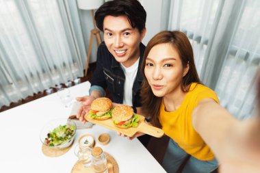 Gülümseyen ev sahibi aşçıların akıllı telefonuyla fotoğraf çekerken üst görüntüsü yemek programında çift hamburger tutarken sosyal medya kanalında ev yapımı salata tabağıyla kolaylıkla görülebiliyor. İnfobahn.