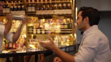 Eski usulde gülümseyen akıllı adam kokteyl içerken, barmen de özel içkiler hazırlıyor. Cuma gecesi lüks bir gişede, gece kulübünde, canlı bir içecekle servis yapmak için sallanıyor. Vinosity.