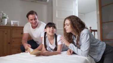 Çocukluk hikayeleri anlatan uyku zamanı, anne ve baba rahat ve rahat yatak odasındaki küçük kızlarına birlikte fantezi kitabı okuyorlar. Modern aile eğlencesi. Titiz