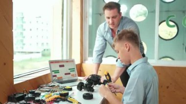 Kafkas öğretmeni öğrencilere araba modelini tamir etmede yardım ediyor ve liseli çocuklar STEM sınıfında robotu tamir etmek için ekipmanları dinlerken programlama sistemi ya da kodlama komutu veriyor. Öğretim