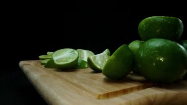 Yakın plan, canlı bir dilim taze kireç kırsal bir ahşap kesme tahtasının üzerinde duruyor. Tazelik ve canlılık yayıyor. Kesme tahtasına konmuş yeşil limon diliminin yarı saydam zarları. Geliştirilebilir.