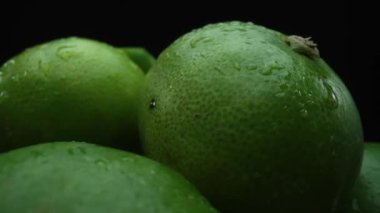 Limon dilimleri titizlikle bir yığın halinde, siyah arkaplana göre dizilmiş. Her bir kireç dilimi çarpıcı detaylar, canlı yeşil rengi ve baştan çıkarıcı dokusu ile yakalanır. Kapatın. Geliştirilebilir.