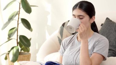 Elinde kahve fincanı olan bir kadın, ders kitabı okur, sosyal ve mesleki teknoloji bilgisini arttırır ya da akıllı bir anne olmak için çocuk yetiştirir. Hayat boyu öğrenme konsepti. Uyumsuzluk.