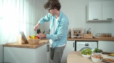 Mutlu baba yemek pişirirken müziğe geçiyor ve modern mutfakta öğle yemeği hazırlıyor. Aktif baba, sebze ve mutfak gereçleri ile çevrili sağlıklı yemek ya da salata yaparken şarkıyla dans ediyor. Pedagoji.
