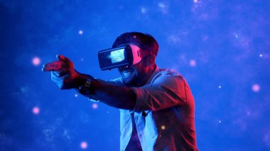 Yetenekli oyuncular silah olarak el ele tutuşup VR gözlük takıp atış oyunu oynayarak metaevrene girebiliyor. Çekici erkek model mavi arka planda dururken hareket ediyor ve oyuncuyu hedef alıyor. Aygıt.