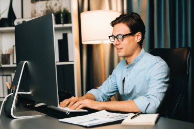 Akıllı iş adamı iş paragrafı dinamik pazarlama analizi planını analiz ediyor. Kağıt kağıtları ve bilgisayar monitörü raporlarını gece evdeki belge verileriyle karşılaştırmak için hazırlıyor. Bireysel.