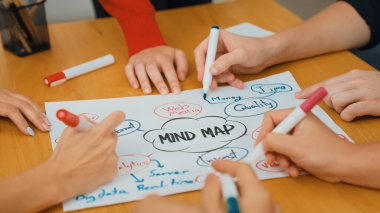 Yetenekli iş adamlarına yakın çekim yapmak beyin fırtınası yapmak, birlikte çalışmak, toplantı masasında zihin haritası ve renkli kalemler kullanarak pazarlama fikrini tartışmak. Eline odaklan. Tertemiz..