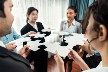 Çok ırklı iş adamları yapboz parçalarını tutuyor ve onları etkili çözüm çözümleri olarak birleştiriyor takım çalışması, ortak görüş ve çeşitli yetenekleri birleştiren ortak hedef. Çok titiz.