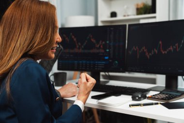 Gülümseyen iş ortakları, kâr borsası ile yumruklarını kaldırarak internet sitesi uygulamasına bakarak ev ofisinin arka tarafındaki dinamik grafikle başarılı oldular. İnfobahn.