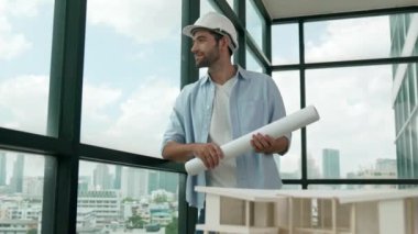 Gökdelen manzarasına bakarken yürüyen profesyonel mimar mühendisi. Masaya yerleştirilmiş ev modeliyle pencereye bakarken yetenekli proje yöneticisi proje planını tutuyor. Tasarım. İzleme