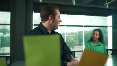 Profesyonel iş adamları yaratıcı pazarlama fikrini modern ofiste tartışırlar. İş adamları cam tahtada yapışkan notlar kullanarak finansal plan üzerinde çalışıyor. Yönlendirici.