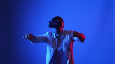 Akıllı oyuncu motosiklet sürerken yarış oyunu oynuyor. Günlük kıyafetleri olan, sanal gerçeklik gözlüğü takan ve meta veriye veya sanal dünyaya giren bir erkek model. Teknoloji. Aygıt.