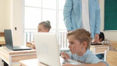 Kafkasyalı öğretmen Amerikan öğrenci kodlama mühendisliğine yardım ederken çeşitli öğrenciler yapay zeka yazılımı kullanıyor. Akıllı çekici çocuklar oturuyor ve programlıyor. Eğitim. Pedagoji.