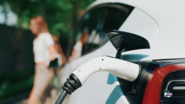Yavaş çekim odaklı EV elektrikli araba yeşil sürdürülebilir şehir açık hava bahçesinde şarj çift bulanık arka planı şehir elektrikli araç iç organları için temiz şarj edilebilir
