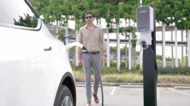 Yavaş çekim adamı, EV şarj aletini şehrin alışveriş merkezinin otoparkındaki şarj istasyonundan şarj etmek için kullandı. Sürdürülebilir şehirde EV aracı tarafından şarj edilebilir enerji olarak kullanıldı.