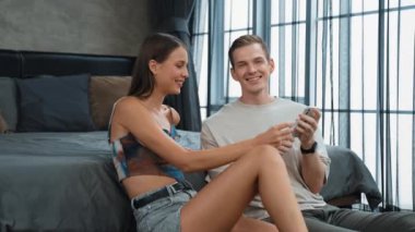 Genç çift, kredi kartıyla ödemek için internet üzerinden ödeme uygulaması ve dijital cüzdan kullanarak yatak odasında oturuyor. Mobil internet üzerinden alışveriş ve modern alımlar. Düzenle