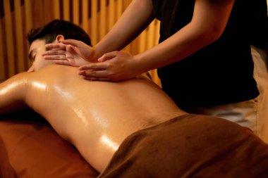 Beyaz erkek müşteri stres önleyici spa masajının keyfini çıkarıyor ve lüks otel ya da oteldeki ortam kaplıcalarında sıcak mum ışığında güzellik teniyle eğleniyor. Sessiz.