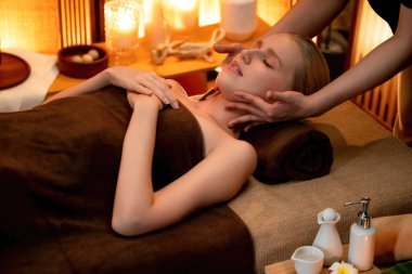 Beyaz kadın stres önleyici kafa masajı yapmaktan ve lüks otel veya otelde sıcak mum ışığında yüz güzelliği eğlencesi yapmaktan zevk alıyor. Sessiz.