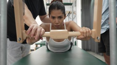 Pilates Cadillac masasında bar tabanlı bir alıştırmada bir müşteriye yardım eden eğitmen. Cadillac 'ta kuğu dalışı yapan kadın beden gücünü ve beden eğitimini arttırıyor. Alışkanlık.