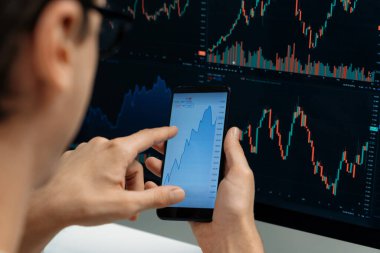 Akıllı borsa yatırımcıları ekranda akıllı telefon ile piyasa borsasını işaret ederek dizüstü bilgisayarın yanı sıra en yüksek dinamik yatırım oranını göstererek, modern işyerindeki veri planlamasına odaklanıyorlar. Bireysel.