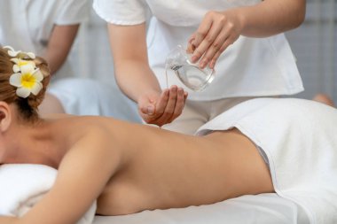 Masör elleri çiftlerin sırtına aroma yağı döküyor. Masözler lüks otellerdeki kaplıca salonundaki müşteriler için yağ masajı prosedürü hazırlıyorlar. Aroma yağı vücut masajı konsepti. Sessiz.