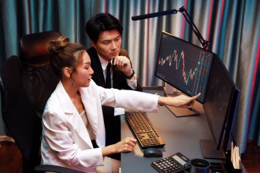 Gülümseyen Asyalı tüccarlar dinamik borsa verilerine işaret ediyor. Gece vakti internet sitesinde kar etme programı. Veri raporunda para birimi değeri analiz ediliyor. İnfobahn.