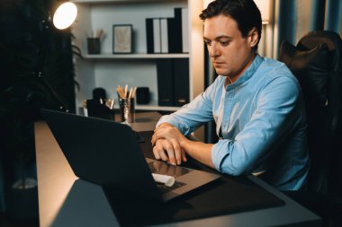 Akıllı iş adamı, gece vakti mavi perde arkasında iş hedefi olan finansal teknoloji veri raporlarını analiz etmek için veritabanı stoklarını araştırmak üzere dizüstü bilgisayarda uzaktan çalışıyor. Bireysel.