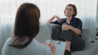 Psikologla ruh sağlığı terapisi gören üzgün travma sonrası stres bozukluğu olan bir kadın. Yaşam sonrası depresyon veya keder. Hayal kırıklığına uğramış genç bir kadın klinikteki duygular hakkında prim psikoloğuyla konuşuyor.