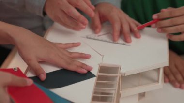 Mimari ekipman kullanarak yavaş çekim ev tasarımcısı bir plan çizerken, iç mimari tasarımcı da müşterilerin talebine göre renk örneklerinden uygun renkler seçiyor. Değiştirilmiş