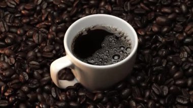 Kahve ya da kahve çekirdekli espresso manzarası. Taze kavrulmuş kahve çekirdeğini yakın çekimde ahşap masanın etrafına bir fincan americano ve aromatik akarsu ve tohum dumanı serpin. Geliştirilebilir.