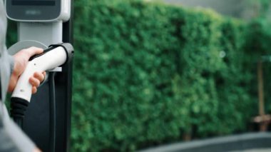 Yaz mevsiminde yeşil sürdürülebilir şehir bahçesinde ağır çekimde çalışan EV elektrikli araba yeşil sürdürülebilir şehirde yeniden şarj edilebilir elektrikli araç iç organları için alışveriş yapan genç çiftlerin yaşam tarzını gösteriyor.