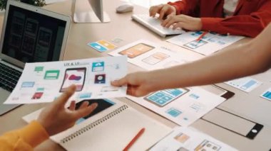 Mobil uygulama için kullanıcı arayüzü prototipini ofis çalışanlarına sunan harika bir şirket çalışanı. UX UI tasarımcısı kağıt üzerinde simge tasarımının işlevini açıklıyor. Sinerjik