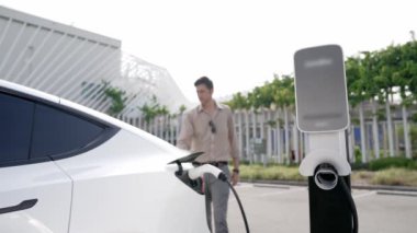 Yavaş çekim adamı, EV şarj aletini şehrin alışveriş merkezinin otoparkındaki şarj istasyonundan şarj etmek için kullandı. Sürdürülebilir şehirde EV aracı tarafından şarj edilebilir enerji olarak kullanıldı.