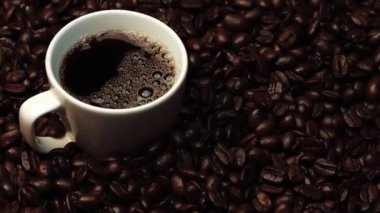 Kahve ya da kahve çekirdekli espresso manzarası. Taze kavrulmuş kahve çekirdeğini yakın çekimde ahşap masanın etrafına bir fincan americano ve aromatik akarsu ve tohum dumanı serpin. Geliştirilebilir.