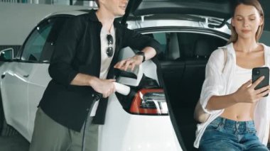 Yavaş çekim çift uygulama ekranında elektrikli araba aküsü şarj durumu, menzil ve şarj limitini kontrol ediyor. Akıllı teknoloji aygıtı, EV arabasının araba aküsündeki elektrik depolama verilerini şarj ettiğini gösteriyor..