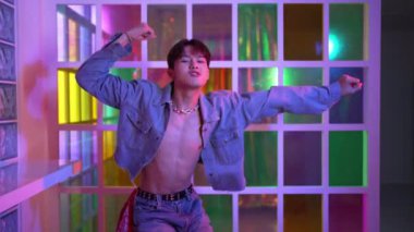 Kameraya bakarken kollarını esneten seksi kıyafetli Asyalı dansçı. Profesyonel sanatçı gece kulübünde renkli neon ışıkları canlı bir şekilde dururken serbest stil dansı yapıyor. Mutluluk.