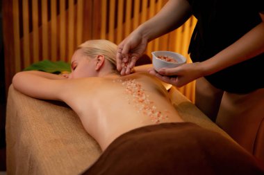 Lüks spa salonlarında sıcak mum ışığında cilt bakımı yaptıran kadın müşteri. Sağlık Spa vücut fırçasında tuz temizleme güzellik tedavisi. Sessiz.